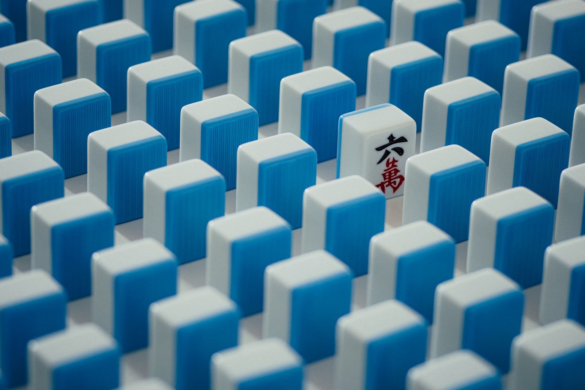 Close-up of blue and white Mahjong tiles — a single tile standing out from the rest